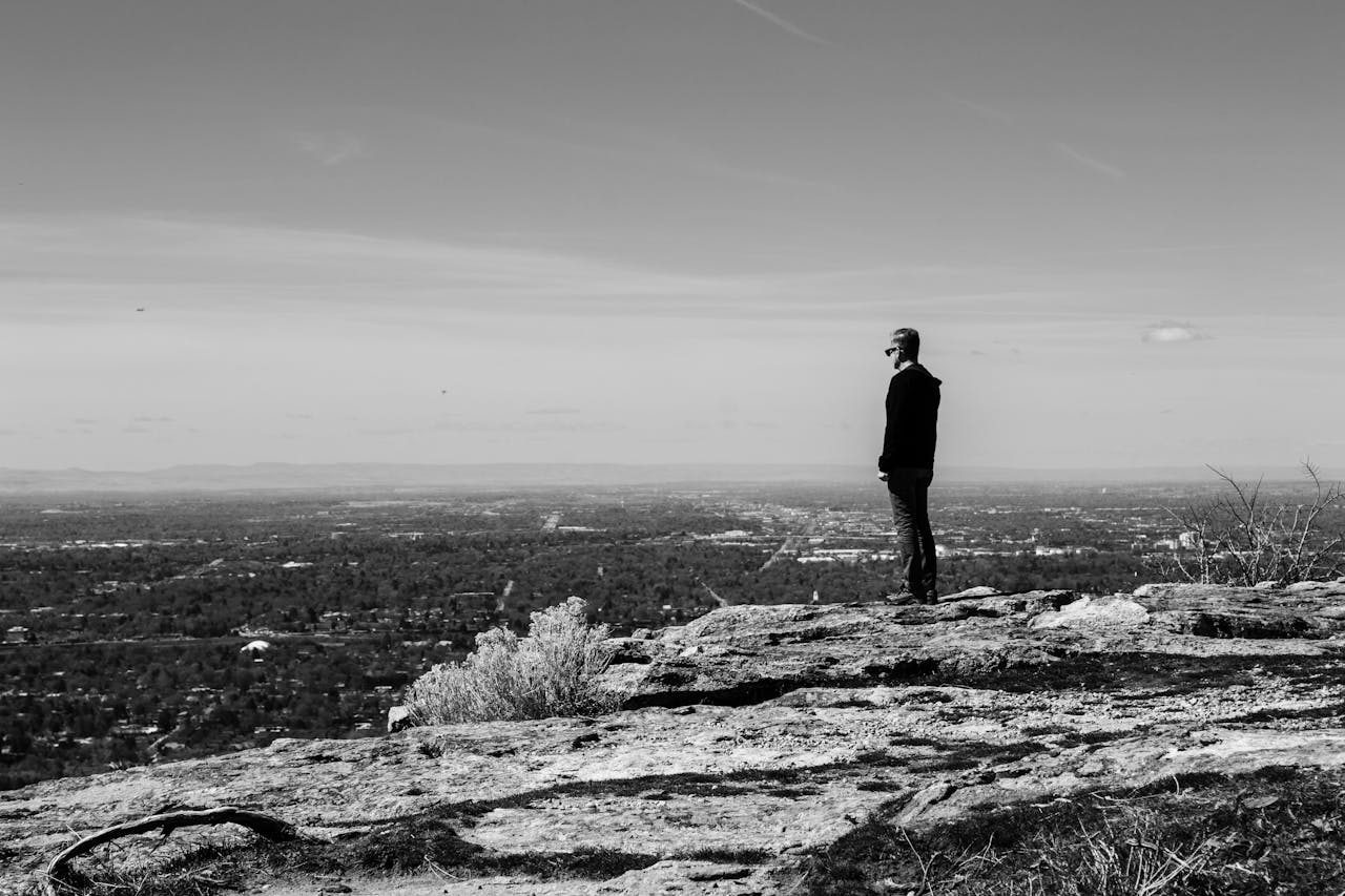 Man standing on a rocky overlook, reflecting on direction and change during a midlife coaching reset