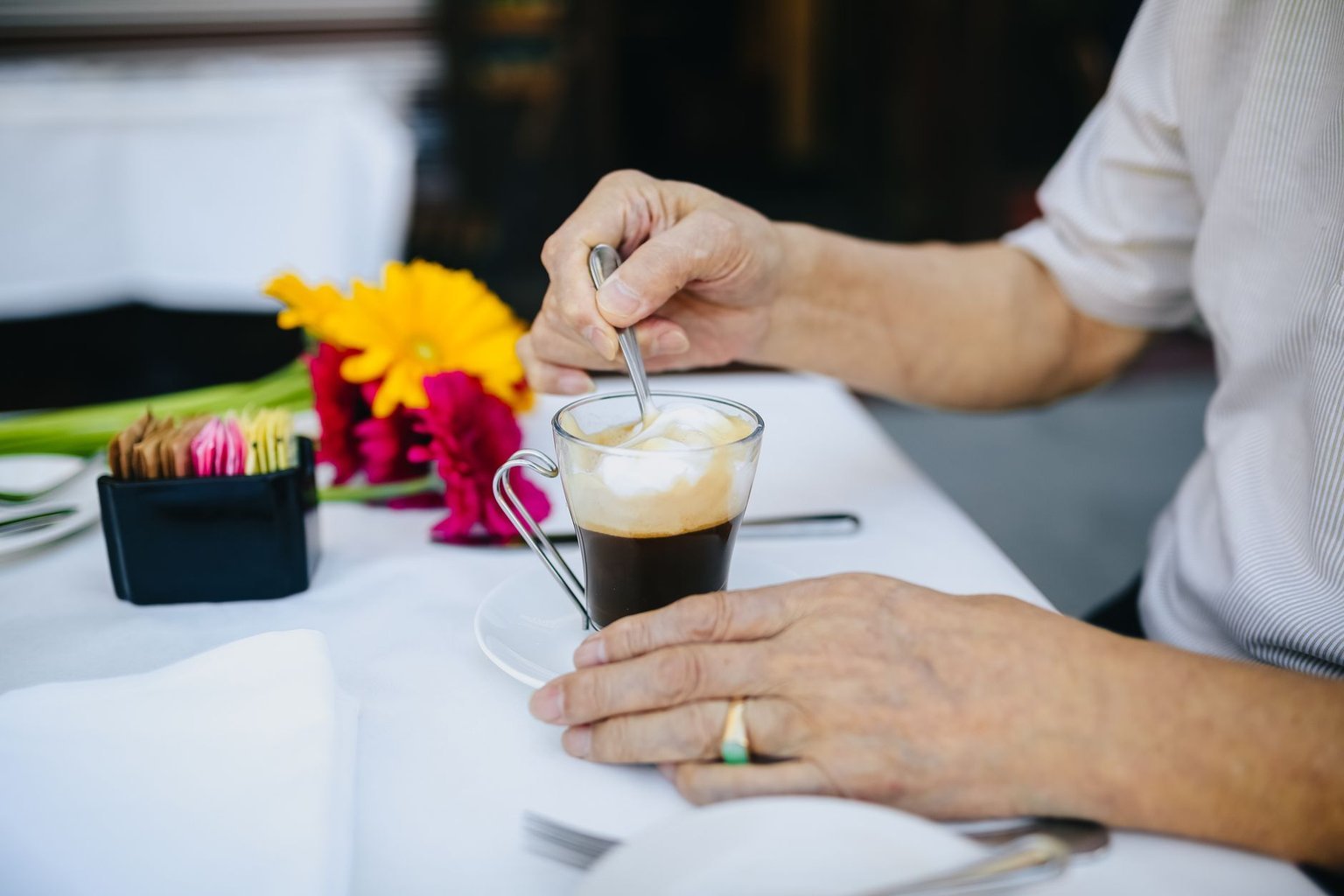 Older man's hands around a coffee cup beside a rain-streaked window