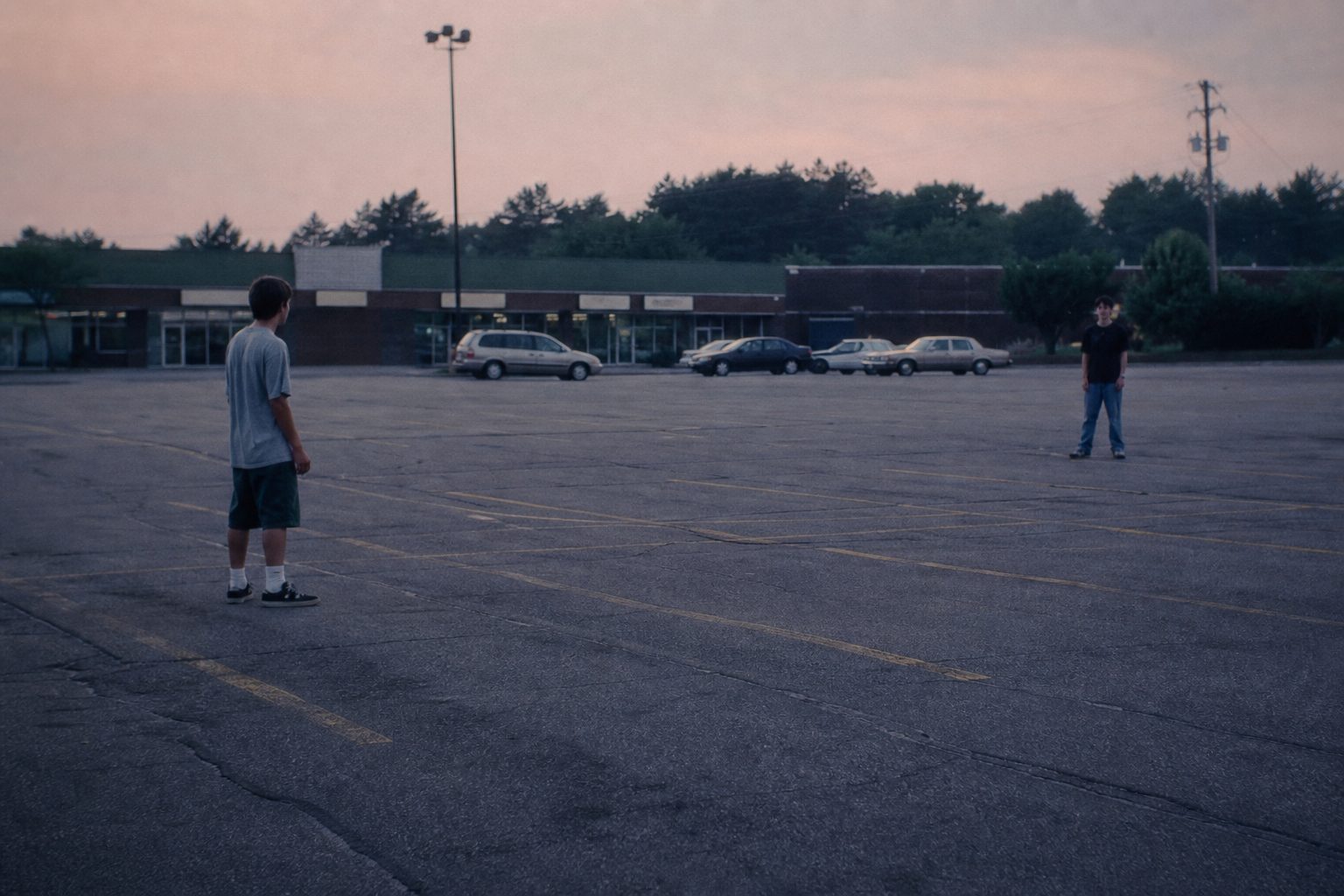 Two teenage boys facing each other across an empty parking lot